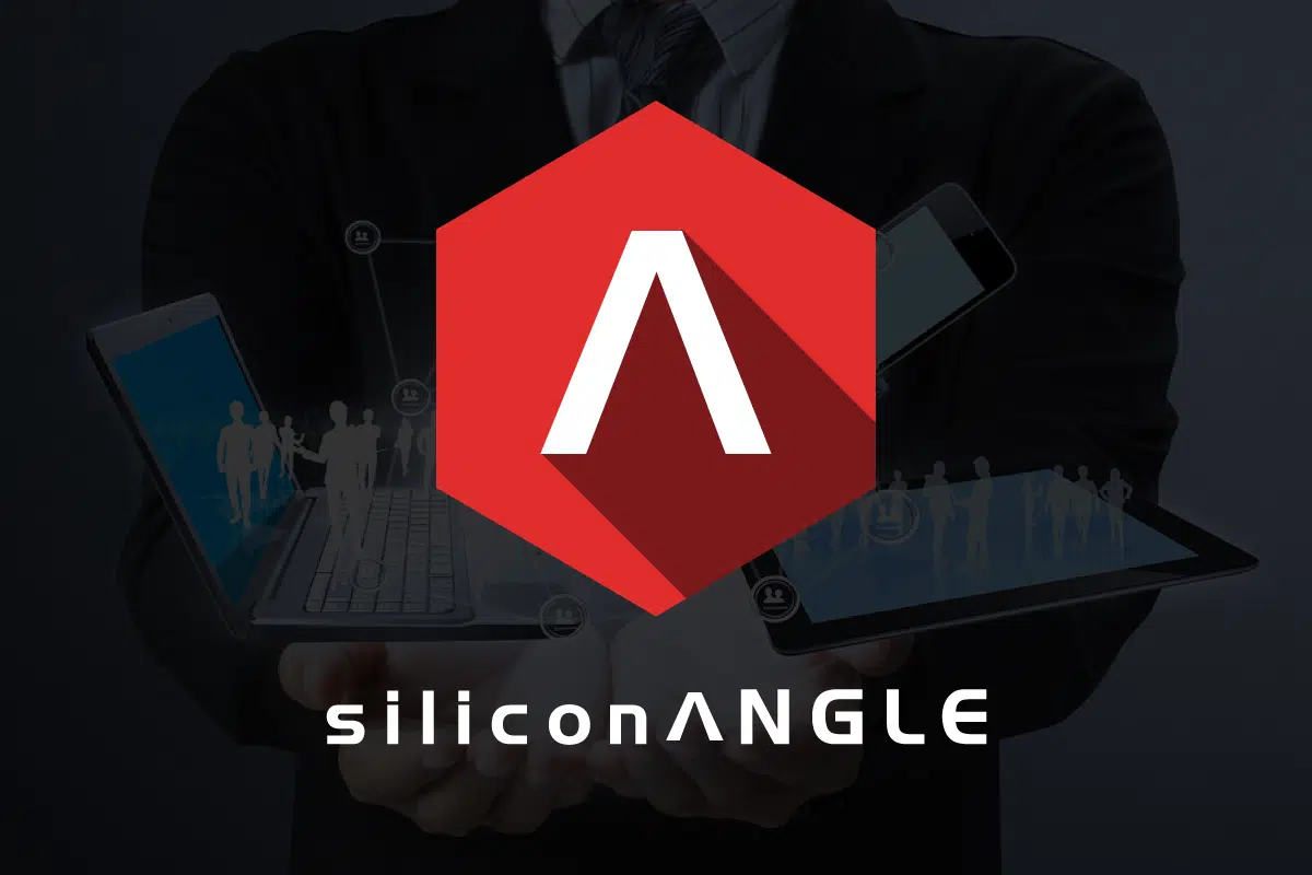 A person in a suit holds digital devices, including a laptop, tablet, and smartphone, with holographic human figures. A red hexagon with a white A is central. siliconANGLE is written at the bottom. The background is dark.